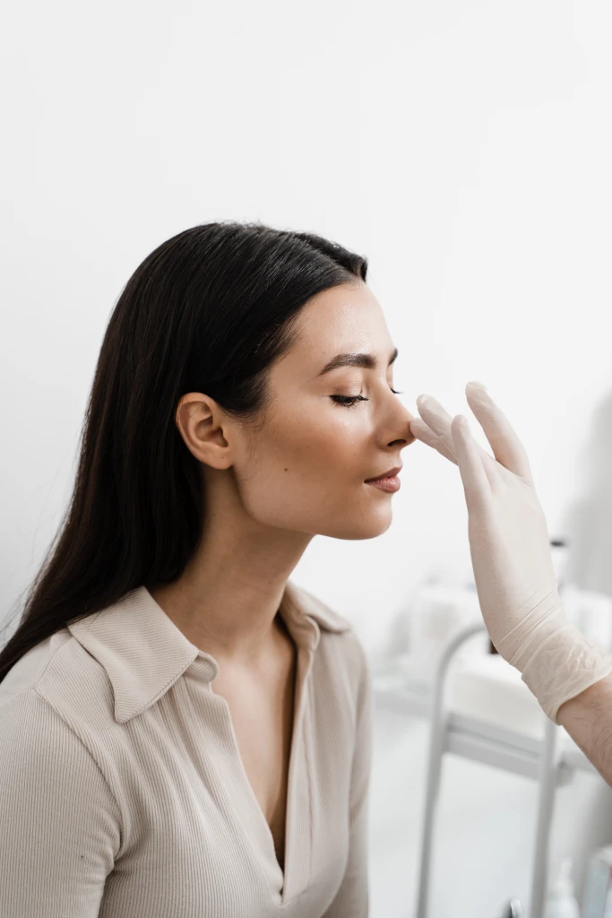 La rinoplastia es una cirugía de remodelación de la nariz para cambiar la apariencia de la nariz y mejorar la respiración El otorrinolaringólogo está tocando la nariz y consultando a una paciente en una clínica médica antes de la cirugía de septoplastia